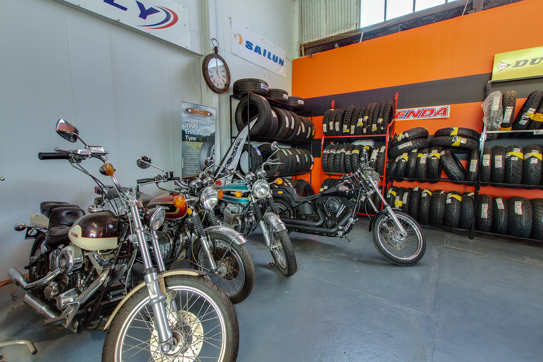 Classic motorbikes parked in front of racks of road and motocross tyres inside Steel City Tyres