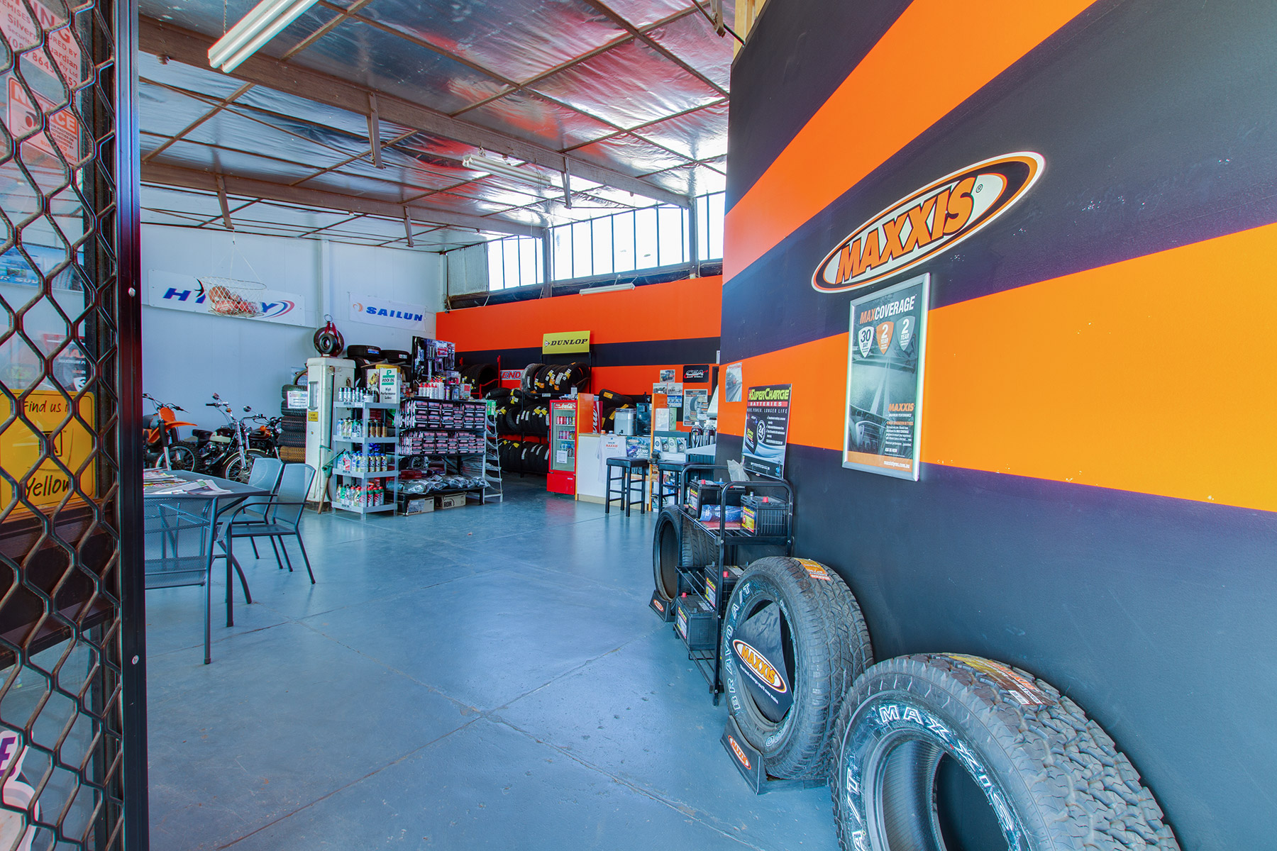 The Steel City Tyres showroom, with its orange and charcoal striped feature wall, tyre display stands and battery rack